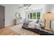 Bright main bedroom features a large window, modern chandelier, and hardwood flooring with a textured rug at 5601 Robinhood Rd, Charlotte, NC 28211