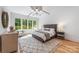 Bright main bedroom features a textured rug, a large window, and a tray ceiling with modern light fixture at 5601 Robinhood Rd, Charlotte, NC 28211
