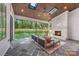 Relaxing sunroom with a brick fireplace, skylights, comfortable seating, and views of the fenced backyard at 5601 Robinhood Rd, Charlotte, NC 28211