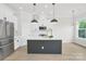 Spacious kitchen featuring white cabinets, stainless steel appliances, an island with seating, and stylish pendant lighting at 5946 Ardrey Kell Rd, Charlotte, NC 28277