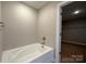 Bright bathroom featuring a soaking tub next to an open doorway to a walk in closet at 664 Cape Fear St, Fort Mill, SC 29715