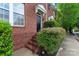 Brick townhome with a black door, landscaped shrubbery, and close proximity to sidewalk at 13838 Hill St, Huntersville, NC 28078