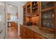 Butler pantry featuring custom cabinetry with wine storage, granite countertops, and hardwood floors at 19679 Wooden Tee Dr, Davidson, NC 28036