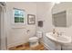 Bathroom featuring a pedestal sink, toilet, and framed window for natural lighting at 20812 Decora Dr, Cornelius, NC 28031
