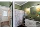 Green bathroom featuring a vanity with granite countertop, oval mirror, and patterned shower curtain at 303 N Main N St, Granite Quarry, NC 28146