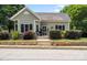 Charming home featuring a well-manicured lawn, stone retaining wall, and inviting front porch with dark shutters at 303 N Main N St, Granite Quarry, NC 28146