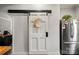 Kitchen area with stainless steel refrigerator, sliding barn door, and white walls at 303 N Main N St, Granite Quarry, NC 28146