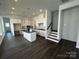 Open-concept kitchen with white cabinets, black island, stainless appliances, and dark hardwood floors leading to stairs at 3117 Beacon Heights Rd, Indian Land, SC 29707