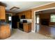 A kitchen features a black oven, black refrigerator, oak cabinets, and is adjacent to an open living area at 3240 St Vincent Dr, Claremont, NC 28610