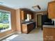 View of the kitchen showcasing oak cabinets and black appliances, adjacent to a bright, sunlit dining area at 3240 St Vincent Dr, Claremont, NC 28610