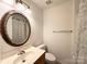 Well-lit bathroom featuring an oval mirror, single sink vanity, and shower with leaf-patterned curtain at 3602 Melrose Cottage Dr, Matthews, NC 28105
