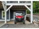 Covered driveway with a red ATV and a gravel driveway surrounded by trees at 434 Breezewood Dr, Belmont, NC 28012