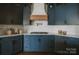 Close up of kitchen with navy cabinets, white backsplash, and stainless gas cooktop at 434 Breezewood Dr, Belmont, NC 28012