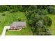 An aerial view of a well-maintained brick home with a vast, manicured lawn bordering a lush forest at 4470 W Bandys Cross Rd, Claremont, NC 28610