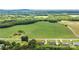 An aerial landscape view displaying homes neighboring a large green field surrounded by lush forested land at 4470 W Bandys Cross Rd, Claremont, NC 28610