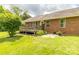 Backyard featuring a brick house, a wooden deck, and a lush green lawn with stone patio at 4470 W Bandys Cross Rd, Claremont, NC 28610