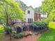 Back exterior view of home showcasing a wooden deck with brick supports and lush landscaping at 5900 Colwick Nw Ct, Concord, NC 28027