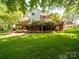 Rear exterior view of home showcasing a large deck, brick accents, and landscaped yard at 5900 Colwick Nw Ct, Concord, NC 28027