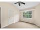 A carpeted bedroom featuring a ceiling fan, window, and interior door at 8302 Holbrook Square Ct, Charlotte, NC 28216