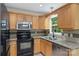 An efficient kitchen offers warm wood cabinets, granite countertops, and black appliances at 8302 Holbrook Square Ct, Charlotte, NC 28216