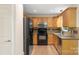 This efficient kitchen has warm wood cabinets, granite countertops, and black appliances at 8302 Holbrook Square Ct, Charlotte, NC 28216