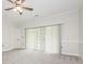 Bright bedroom with gray carpet, ceiling fan, and sliding glass doors with vertical blinds at 8747 Coralbell Ln, Charlotte, NC 28213