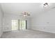 Bright bedroom with gray carpet, ceiling fan, and sliding glass doors to a private balcony at 8747 Coralbell Ln, Charlotte, NC 28213