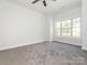 A well-lit bedroom features neutral walls and carpet flooring with a large window offering natural light and providing a pleasant atmosphere at 8747 Coralbell Ln, Charlotte, NC 28213