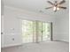 Bright bedroom with gray carpet, ceiling fan, and sliding glass doors to a private balcony at 8747 Coralbell Ln, Charlotte, NC 28213