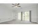 Bright bedroom with gray carpet, ceiling fan, and sliding glass doors to a private balcony at 8747 Coralbell Ln, Charlotte, NC 28213