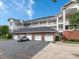 Four white garages beneath three-story condo building with balconies on a partly cloudy day at 8747 Coralbell Ln, Charlotte, NC 28213