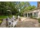 Stone patio with white Adirondack chairs and a modern-style enclosed porch, surrounded by lush greenery at 9001 Peyton Randolph Dr, Charlotte, NC 28277