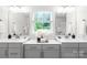 Bathroom featuring double vanity with grey cabinets, white countertops, and a window above at 10901 Greenvale Dr, Harrisburg, NC 28075