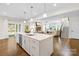 Open-concept kitchen with a large island, stainless steel appliances, pendant lighting, and hardwood flooring at 10901 Greenvale Dr, Harrisburg, NC 28075