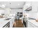 Well-lit, modern kitchen with stainless steel appliances, white cabinetry, and dark wood flooring at 10901 Greenvale Dr, Harrisburg, NC 28075