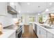 Modern kitchen with white cabinetry, stainless steel appliances, and hardwood flooring overlooking living area at 10901 Greenvale Dr, Harrisburg, NC 28075