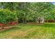 Private backyard featuring lush green lawn, mature trees, and detached outbuilding at 149 Harbor Landing Dr, Mooresville, NC 28117