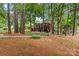 Secluded backyard featuring mature trees, screened porch, stone fireplace, and inviting outdoor seating area at 149 Harbor Landing Dr, Mooresville, NC 28117