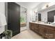 Well-lit bathroom featuring a double vanity, wood cabinets, and a door leading into the connected bedroom at 158 Mattoon St, Charlotte, NC 28216
