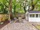Backyard firepit area with gravel, mature trees, and wooden fence at 1605 Allen St, Charlotte, NC 28205