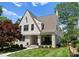 A beautifully landscaped white brick home with a covered front porch and mature trees at 236 Wales Ave, Charlotte, NC 28209