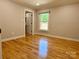 Neutral bedroom featuring gleaming hardwood floors, natural light from the window, and a closet at 456 Brook Valley Ne Ct, Concord, NC 28025