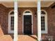 Close-up of the front door with arched windows, decorative black metal door, and brick facade with stately white columns at 456 Brook Valley Ne Ct, Concord, NC 28025