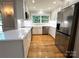 Beautiful kitchen featuring white cabinets, stainless steel appliances, quartz countertops, tile backsplash, and hardwood floors at 456 Brook Valley Ne Ct, Concord, NC 28025