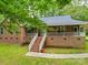 Charming brick home featuring a large front porch with white railings, surrounded by mature trees and landscaping at 4620 Binwhe Ln, Gastonia, NC 28052
