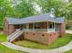 Charming brick home featuring a large front porch with white railings, surrounded by mature trees and landscaping at 4620 Binwhe Ln, Gastonia, NC 28052