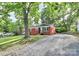 Charming brick home with a gravel driveway framed by lush greenery, blending classic architecture with a serene, natural setting at 4913 Winchester St, Charlotte, NC 28208