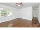 Bright living room featuring gleaming hardwood floors, a ceiling fan, and large windows at 4913 Winchester St, Charlotte, NC 28208