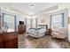 Bright main bedroom with tray ceiling, hardwood floors, large windows with blue curtains at 7016 Bareland Rd, Fort Mill, SC 29707
