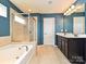Bright bathroom featuring a soaking tub, glass shower, double vanity, and blue walls at 9027 Gray Willow Rd, Charlotte, NC 28227